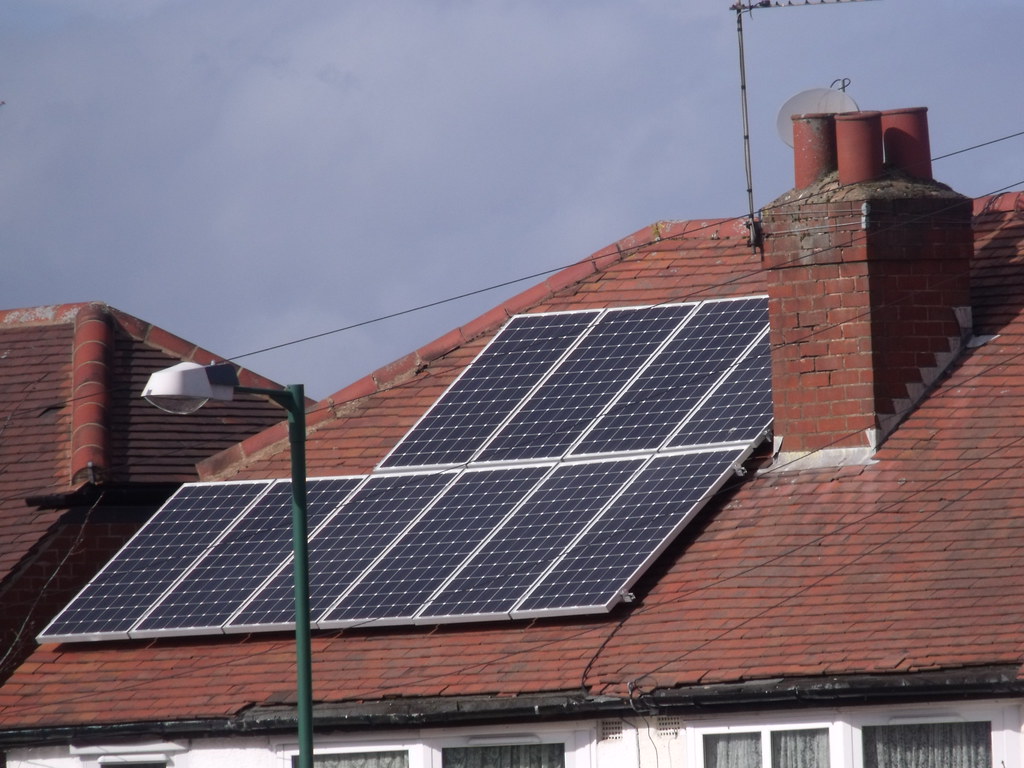 Solar panels fitted on a red tiled roof with chimneys in Northfield, Birmingham