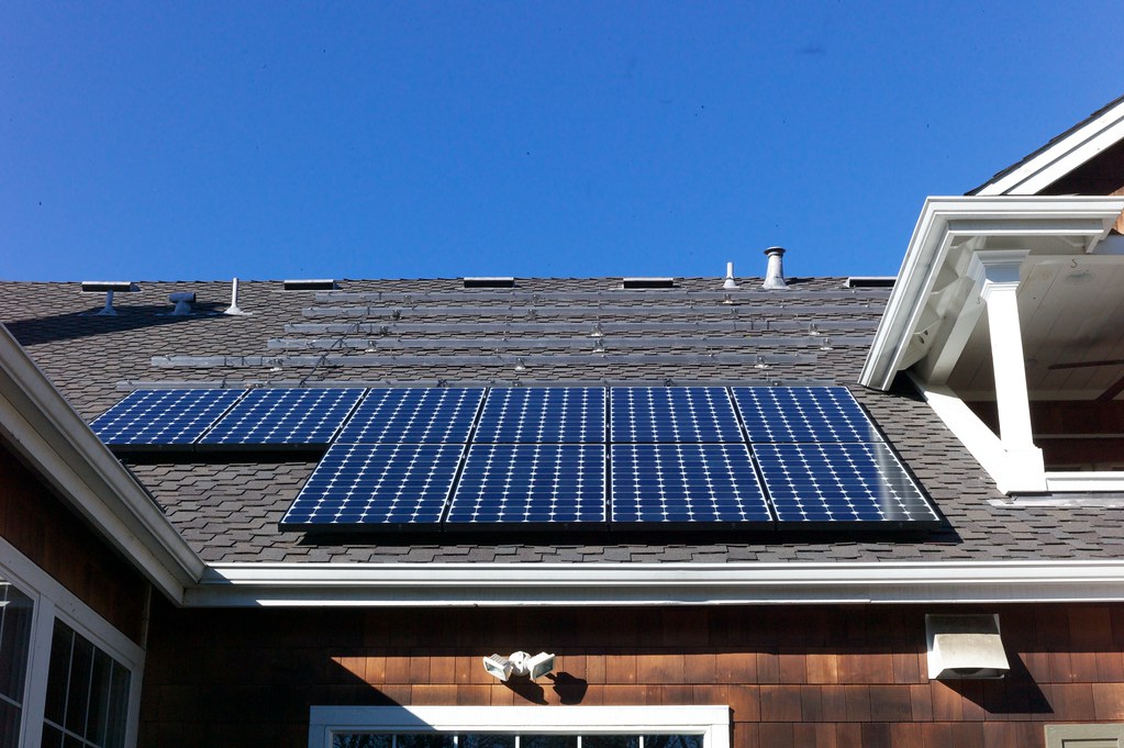 A pitched roof with a row of solar panels fitted below roof vents